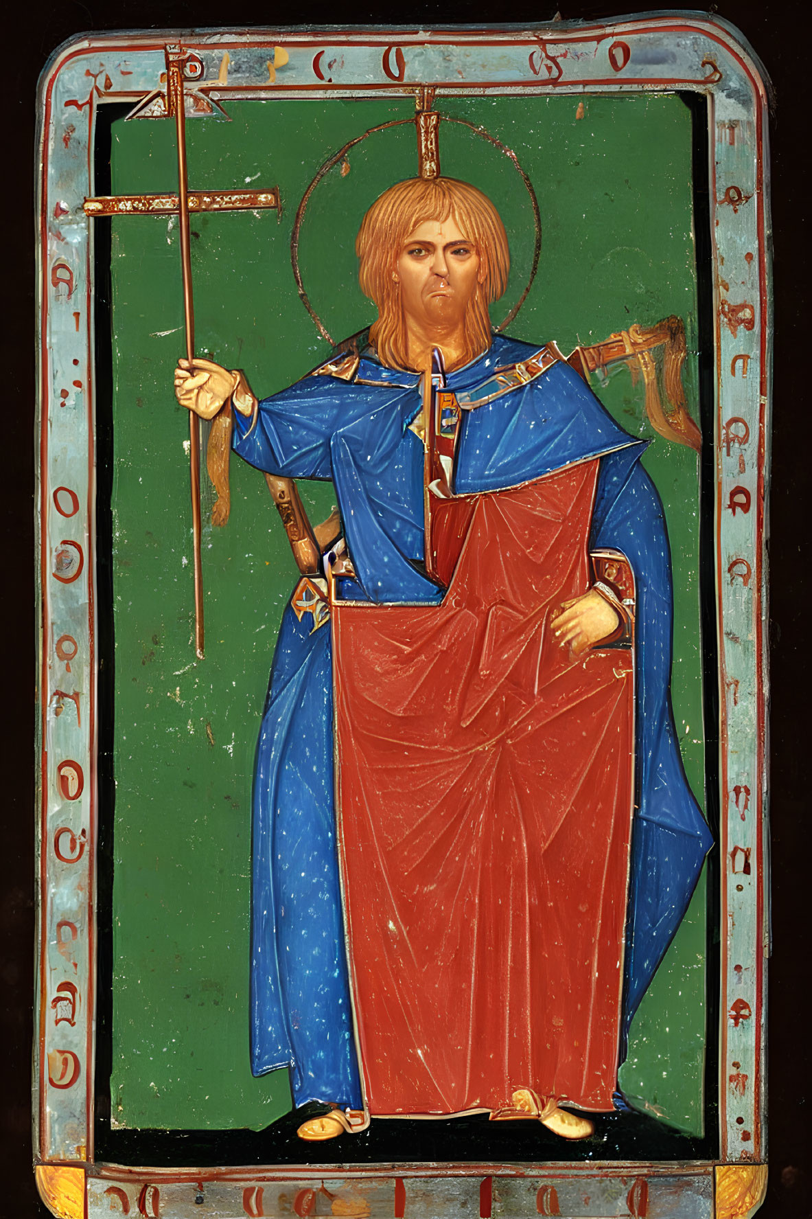 Religious icon with haloed figure in red and blue robes and cross on dark background