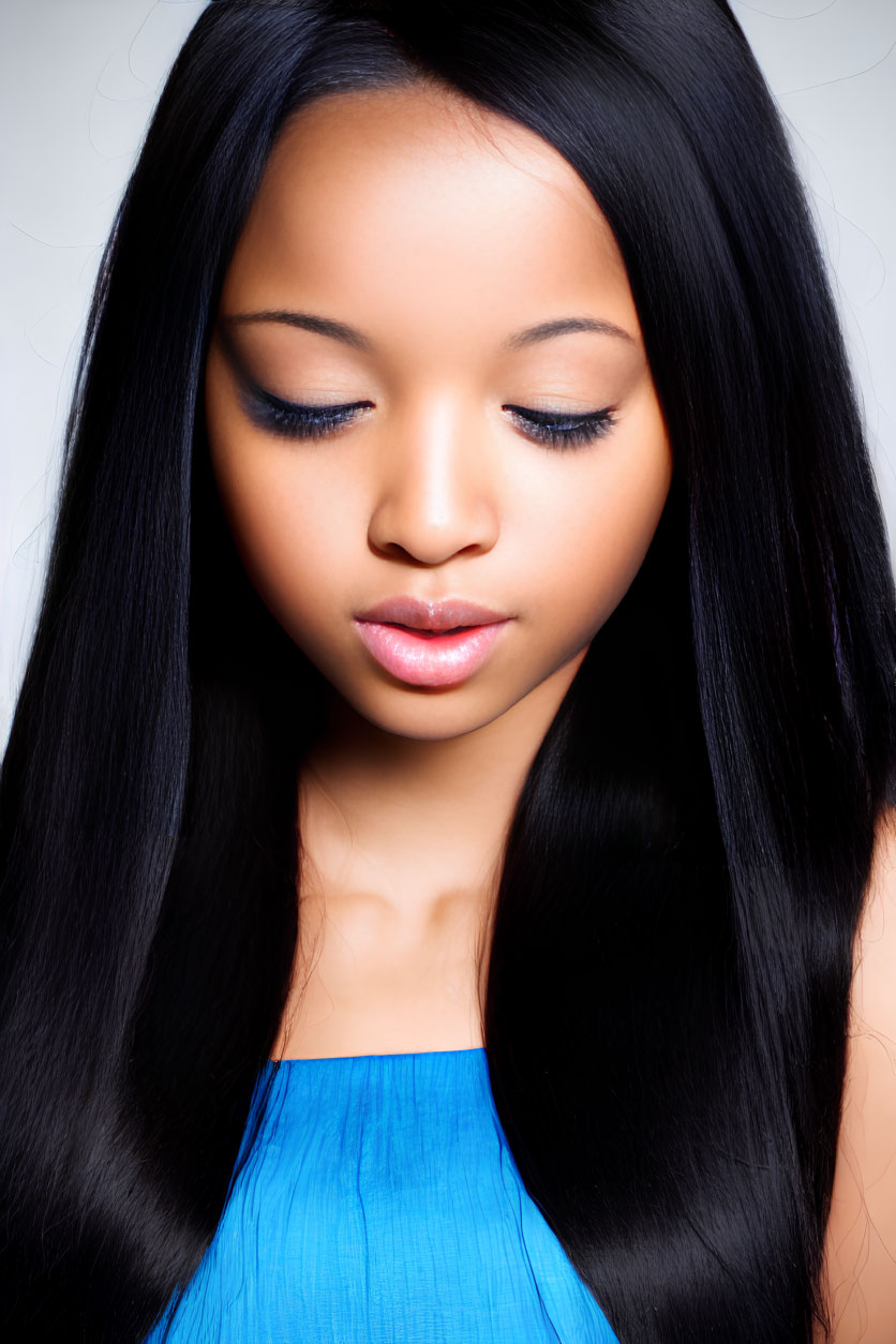 Portrait of young woman with long black hair and blue top