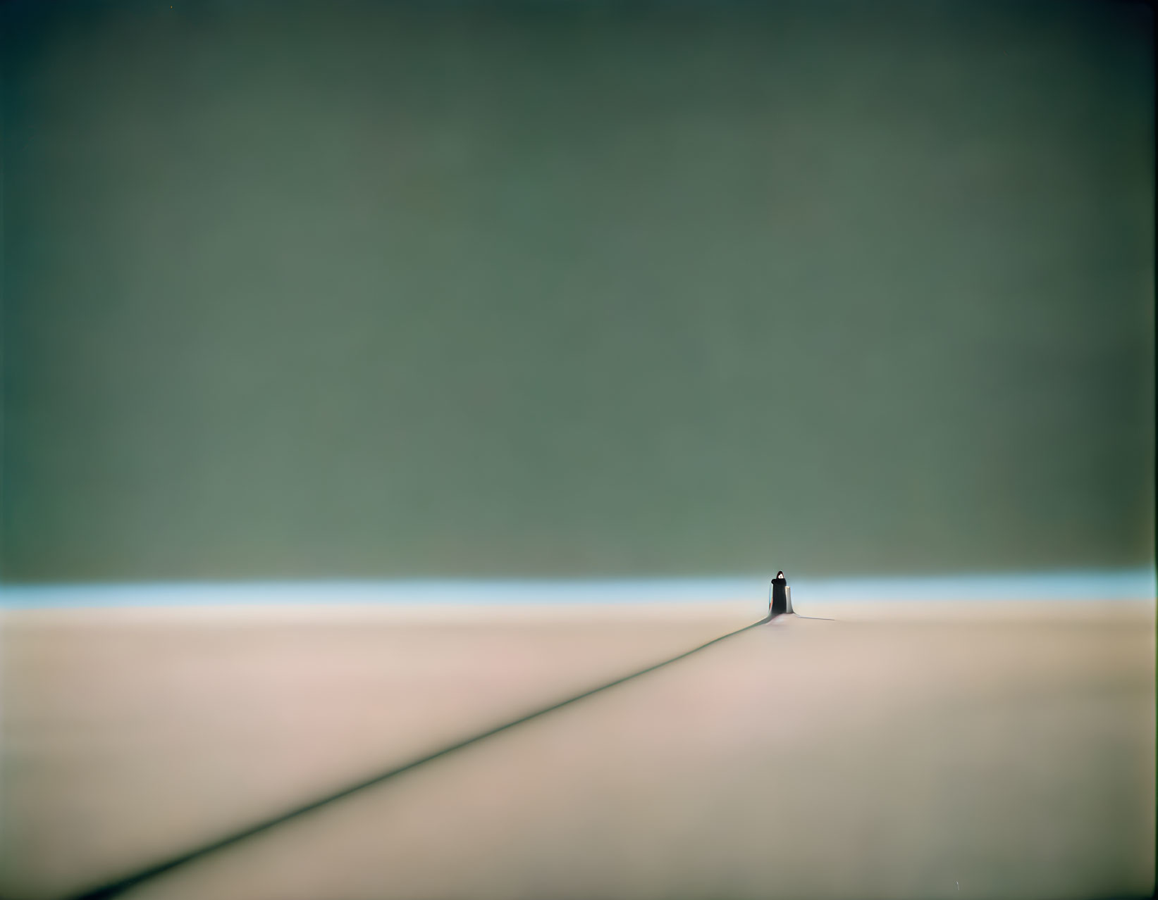 Solitary figure at pathway convergence under vast empty sky