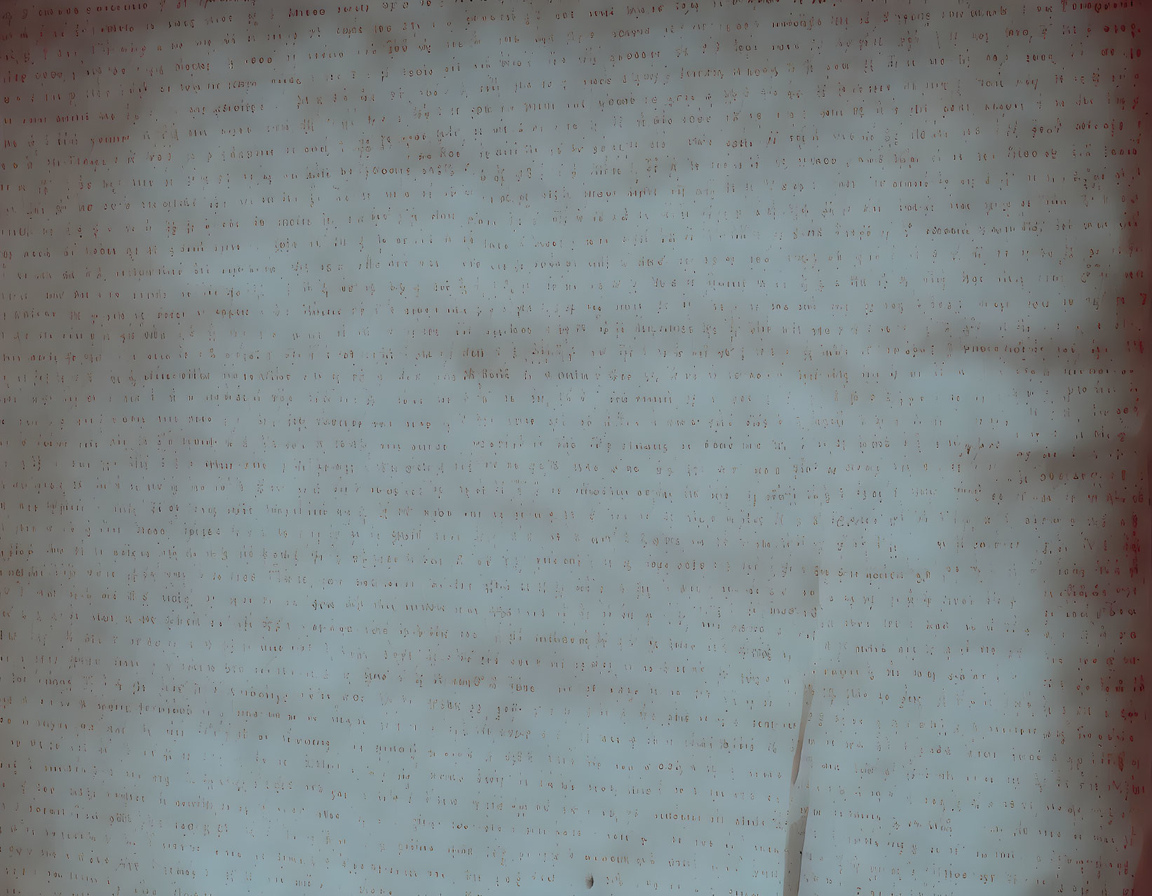 Blurred image of text-covered surface with red spots and streaks