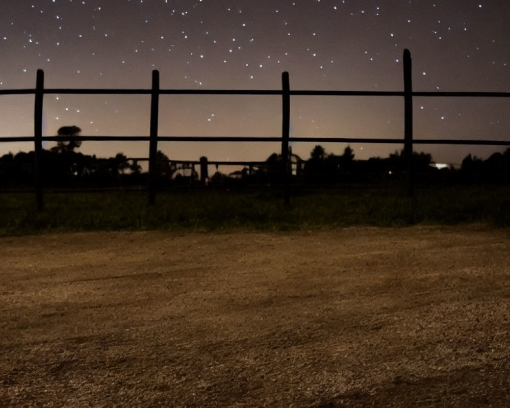 Starry sky over rustic fence and trees at night