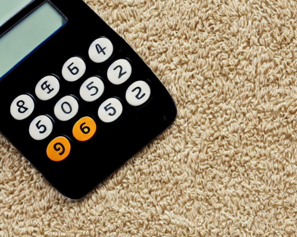 Black Calculator with Orange Stickers on Number 9 Button on Beige Shaggy Carpet