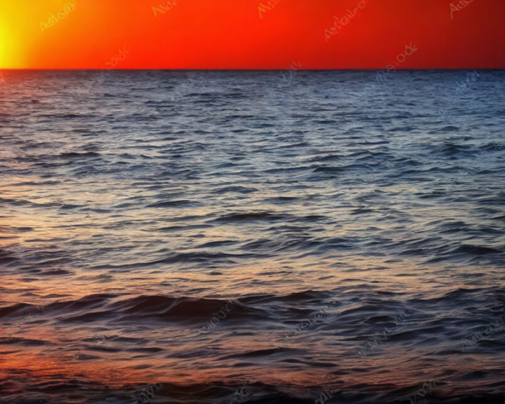 Vibrant red and orange sunset over dark blue ocean waves