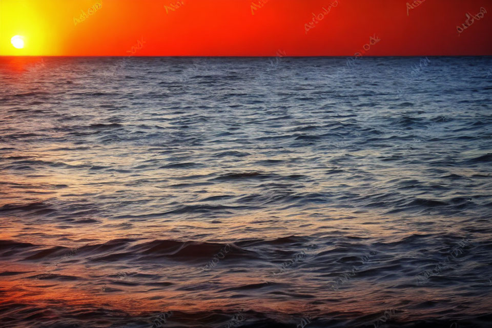 Vibrant red and orange sunset over dark blue ocean waves