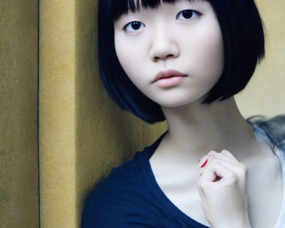 Pensive young woman with bob haircut against yellow wall