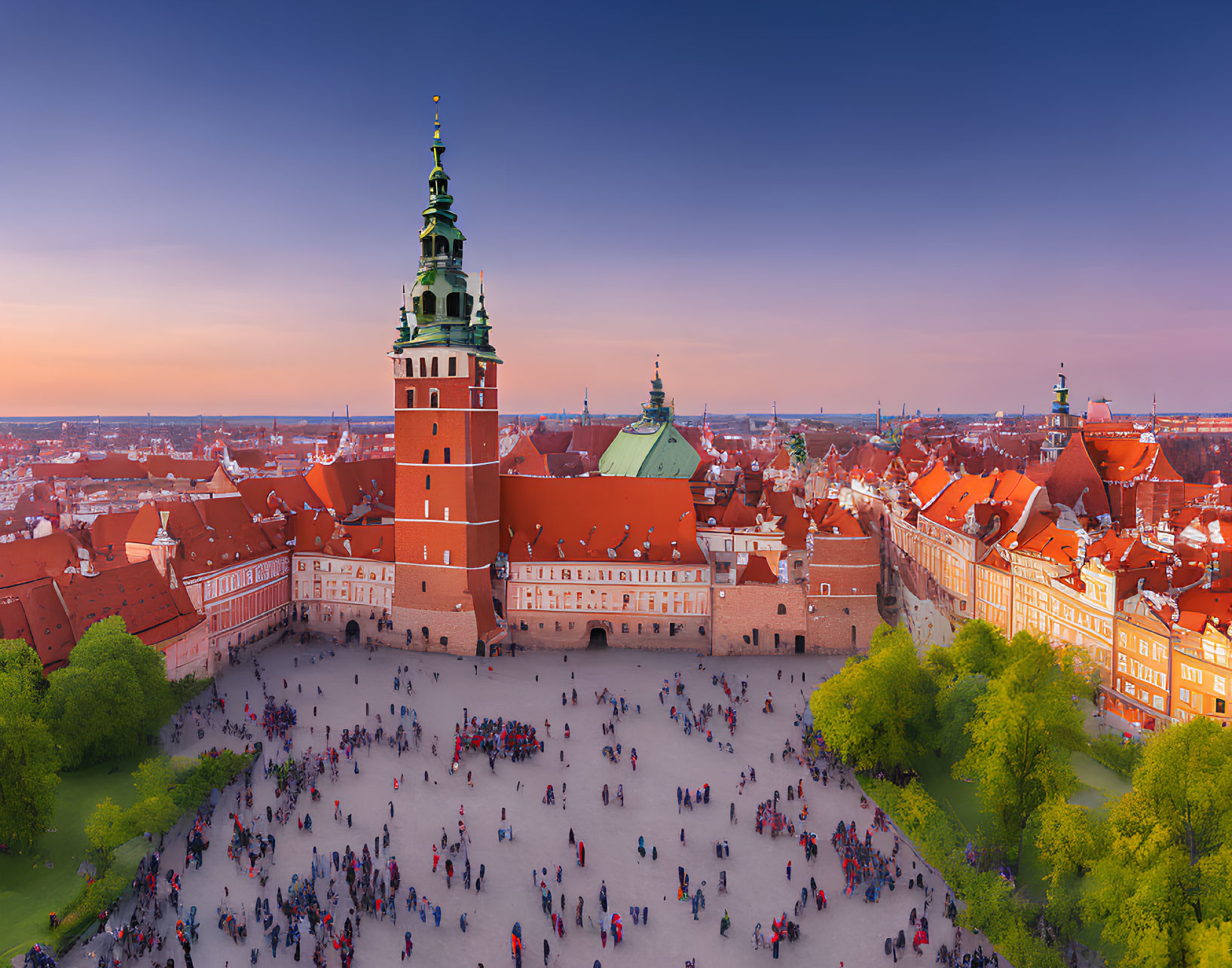 Historic castle with green spire in bustling square at dusk