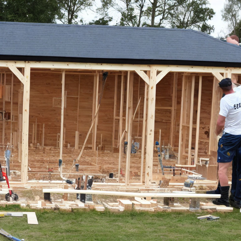 Construction workers building wooden frame for new house with scattered tools and materials.