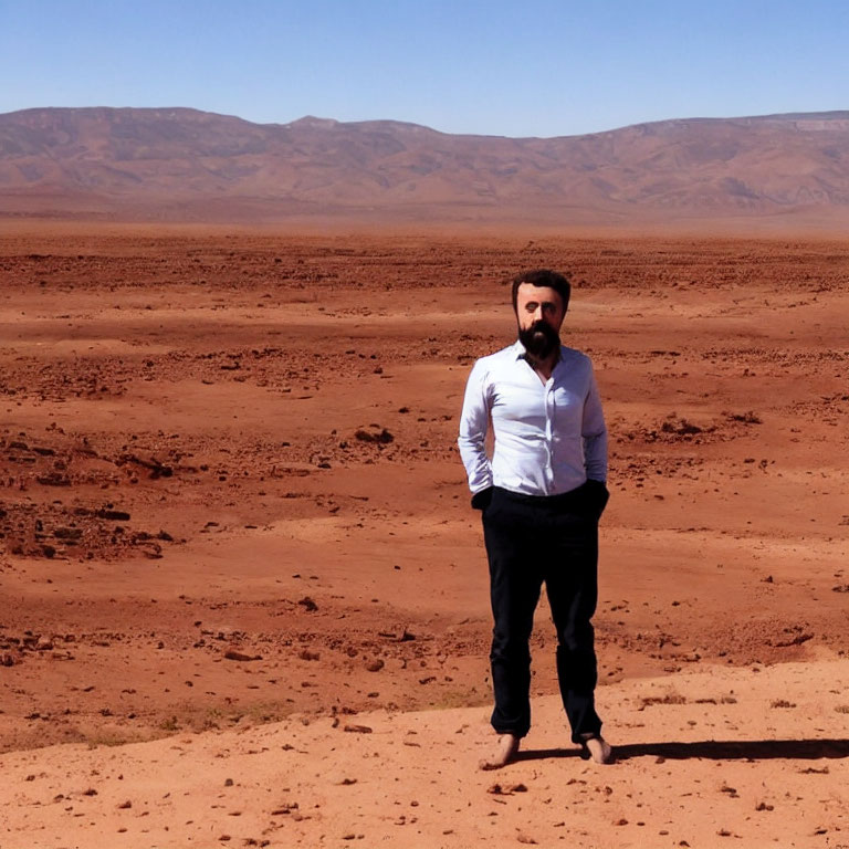 Bearded man in white shirt and black pants on red desert landscape