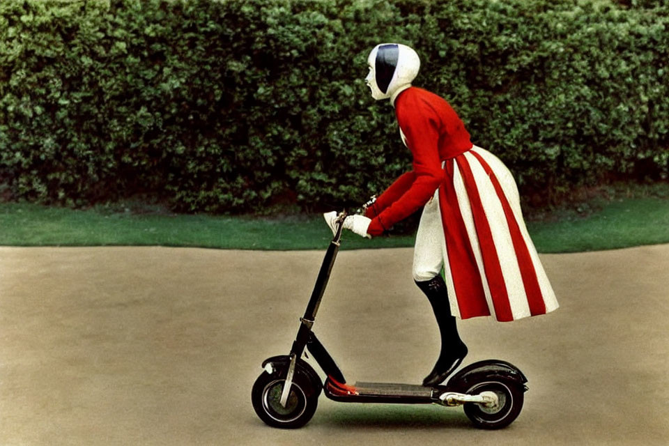 Person in Red and White Motorcycle Helmet Riding Electric Scooter on Hedge-Lined Path