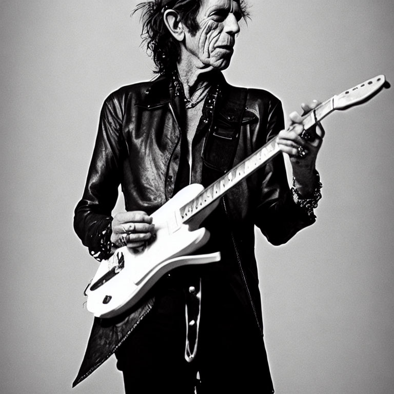 Monochrome photo of man playing white electric guitar in black leather jacket