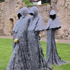 Ghostly figures in draped cloth in grassy area with ruins - eerie atmosphere