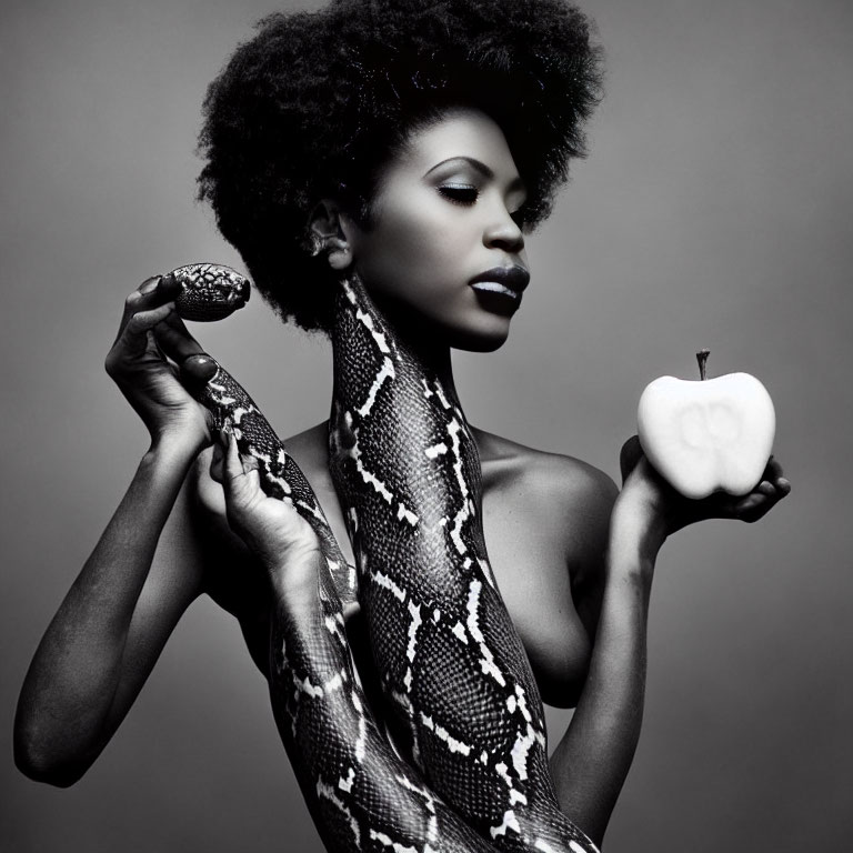 Monochrome portrait of woman with afro hairstyle holding snake and apple