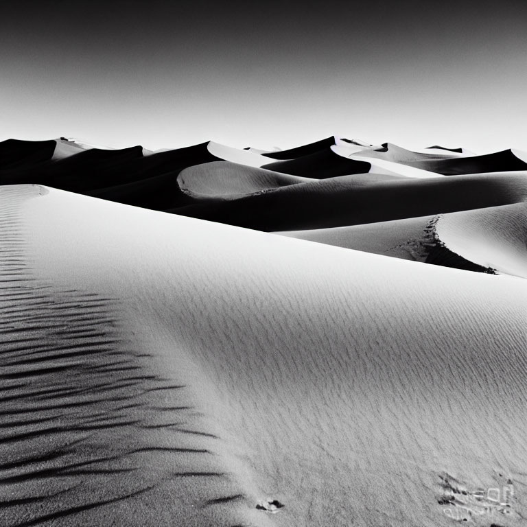 Monochrome photo of sand dunes under clear sky