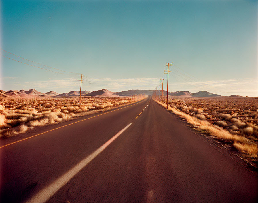 Straight Road Through Rolling Hills at Sunset