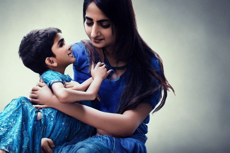 Young boy in blue kurta gazes at woman in traditional Indian attire