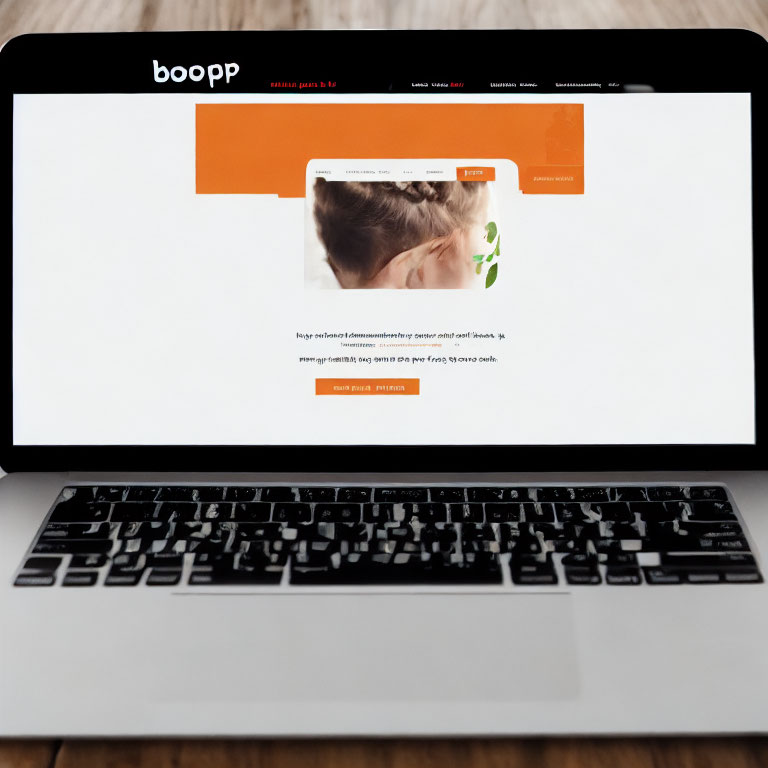 Laptop on Wooden Table Showing White and Orange Website Design with Woman Image and Text