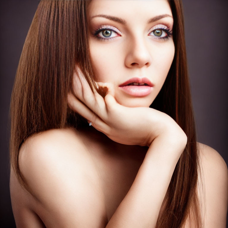 Portrait of woman with long brown hair and blue eyes on gray background