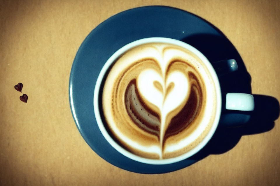 Cappuccino with Heart Latte Art and Coffee Beans on Beige Surface