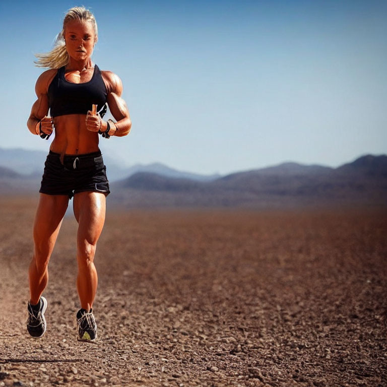 Female athlete running in barren landscape under clear sky