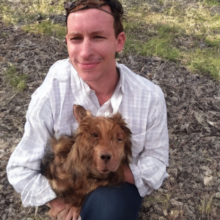 Man with smiling brown dog sitting outdoors