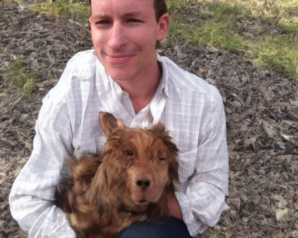 Man with smiling brown dog sitting outdoors