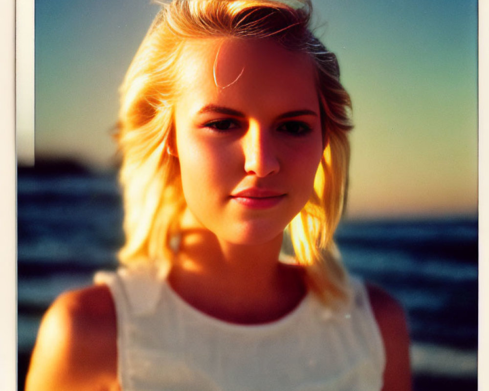 Blonde Woman in White Top at Sunset on Beach with Calm Expression