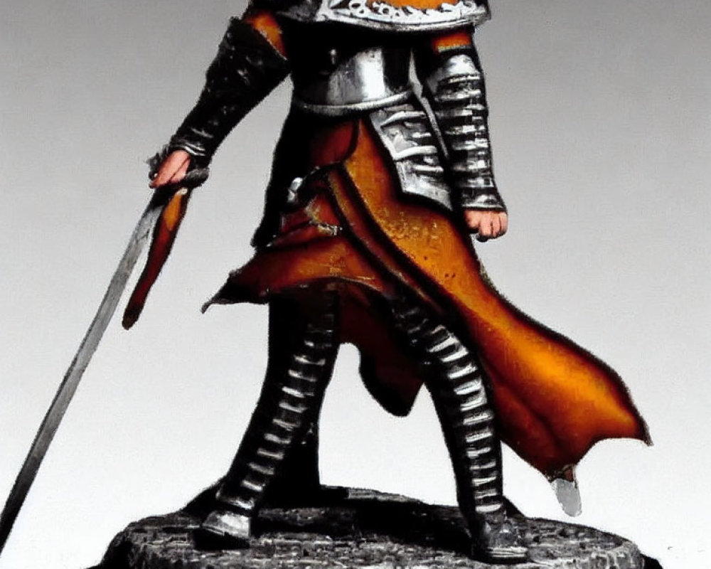 Miniature knight figurine in plate armor with red cape and sword on rocky base