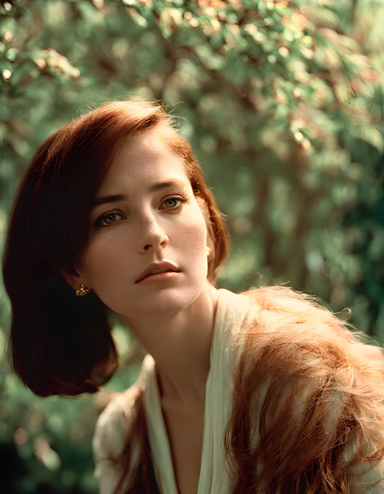 Auburn-haired woman with fair skin gazing into distance in sunlight.