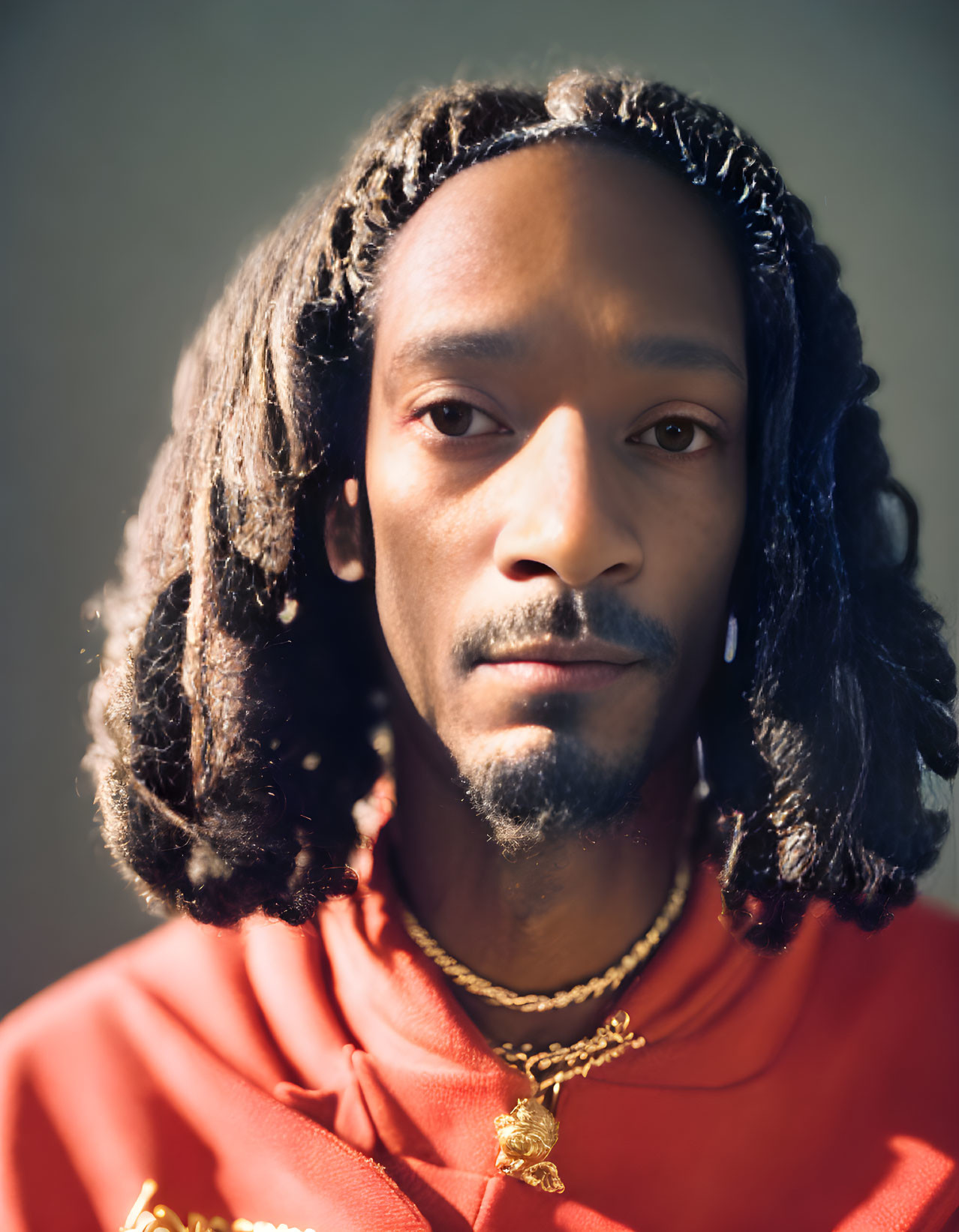 Man with Braided Hair in Red Hoodie and Gold Necklaces