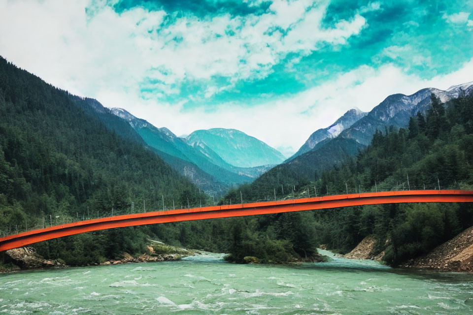 Red bridge over turbulent river in lush forest and mountains under cloudy sky