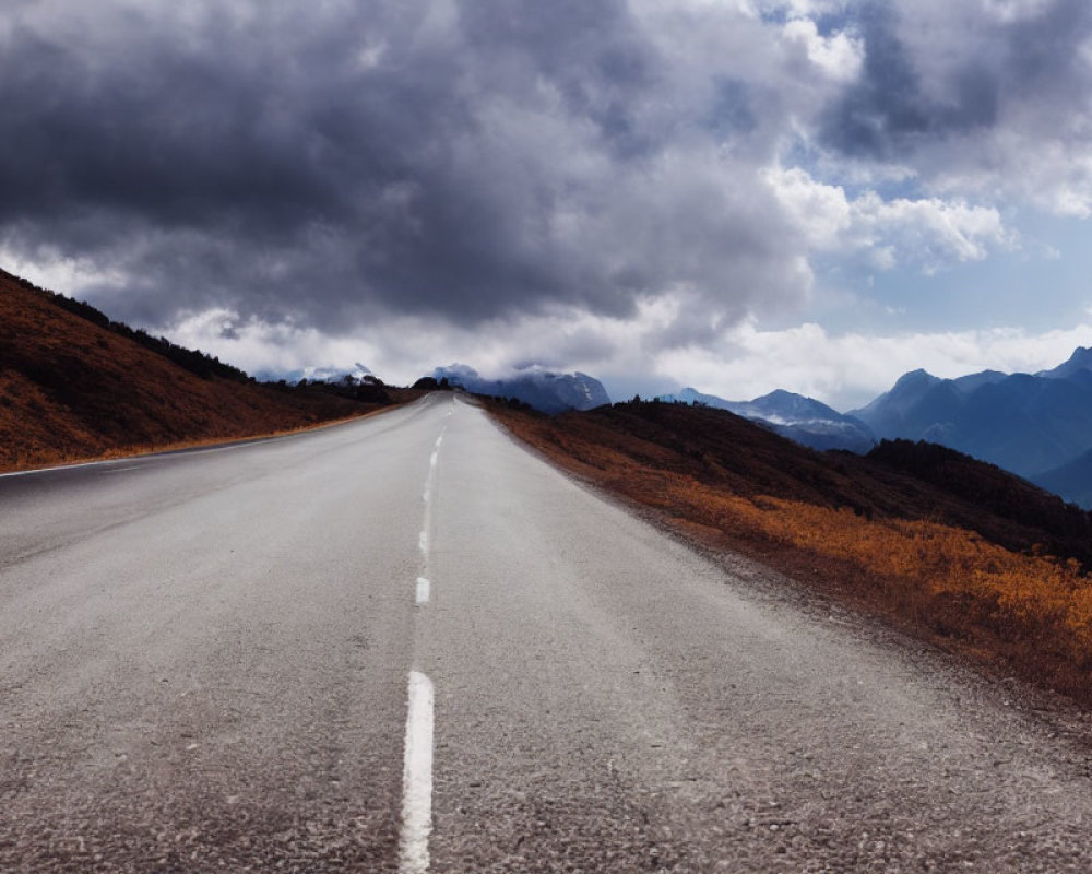 Dramatic sky over empty mountain road with autumn foliage