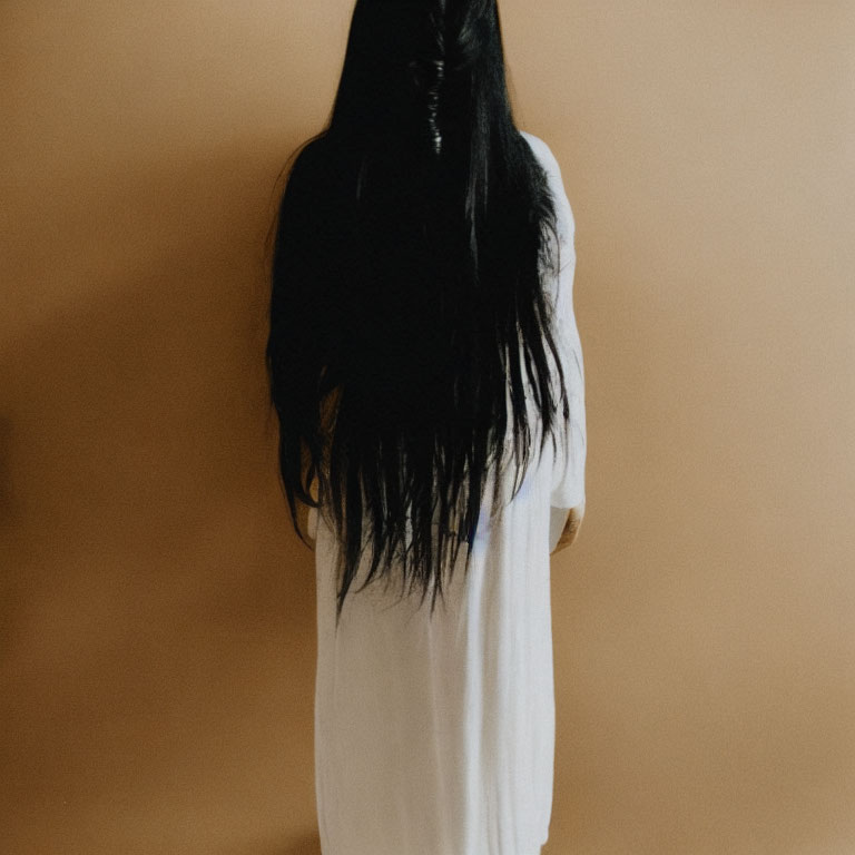 Long Black-Haired Person in White Dress on Beige Background