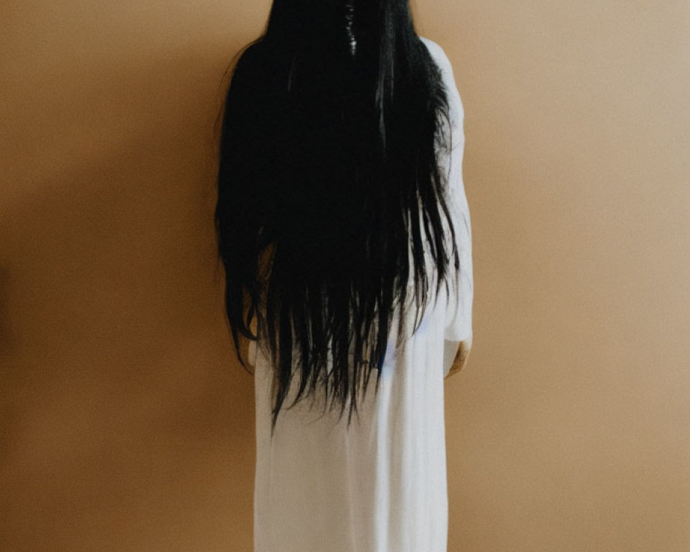 Long Black-Haired Person in White Dress on Beige Background