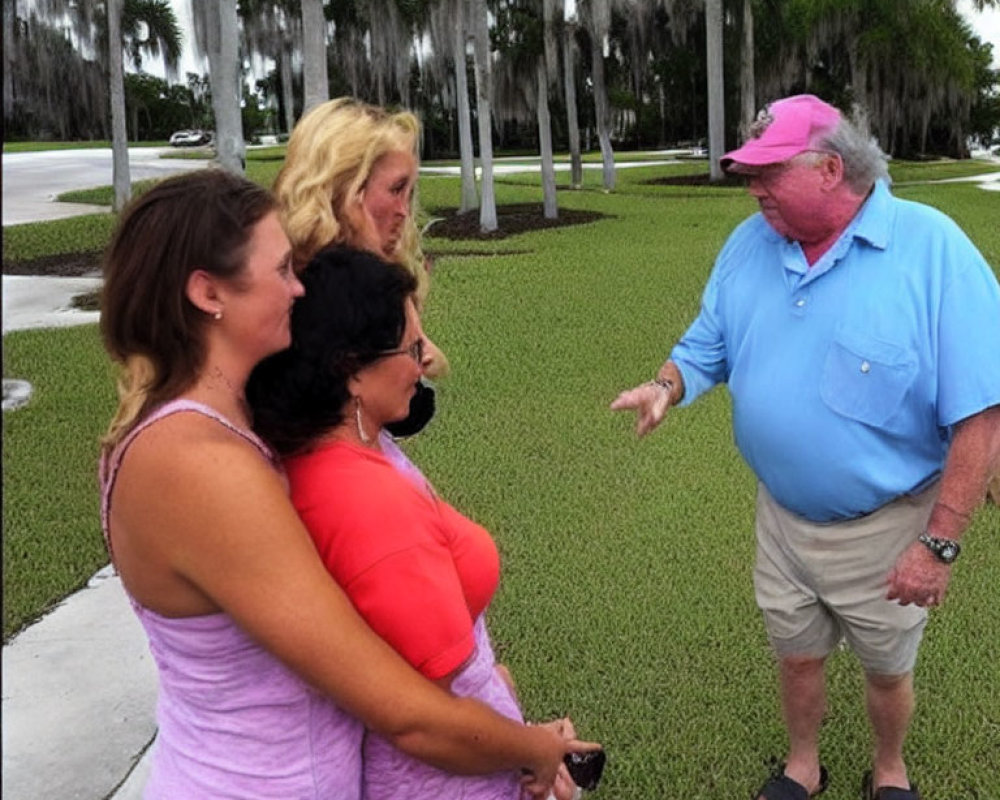 Four individuals conversing outdoors among palm trees and cloudy sky.