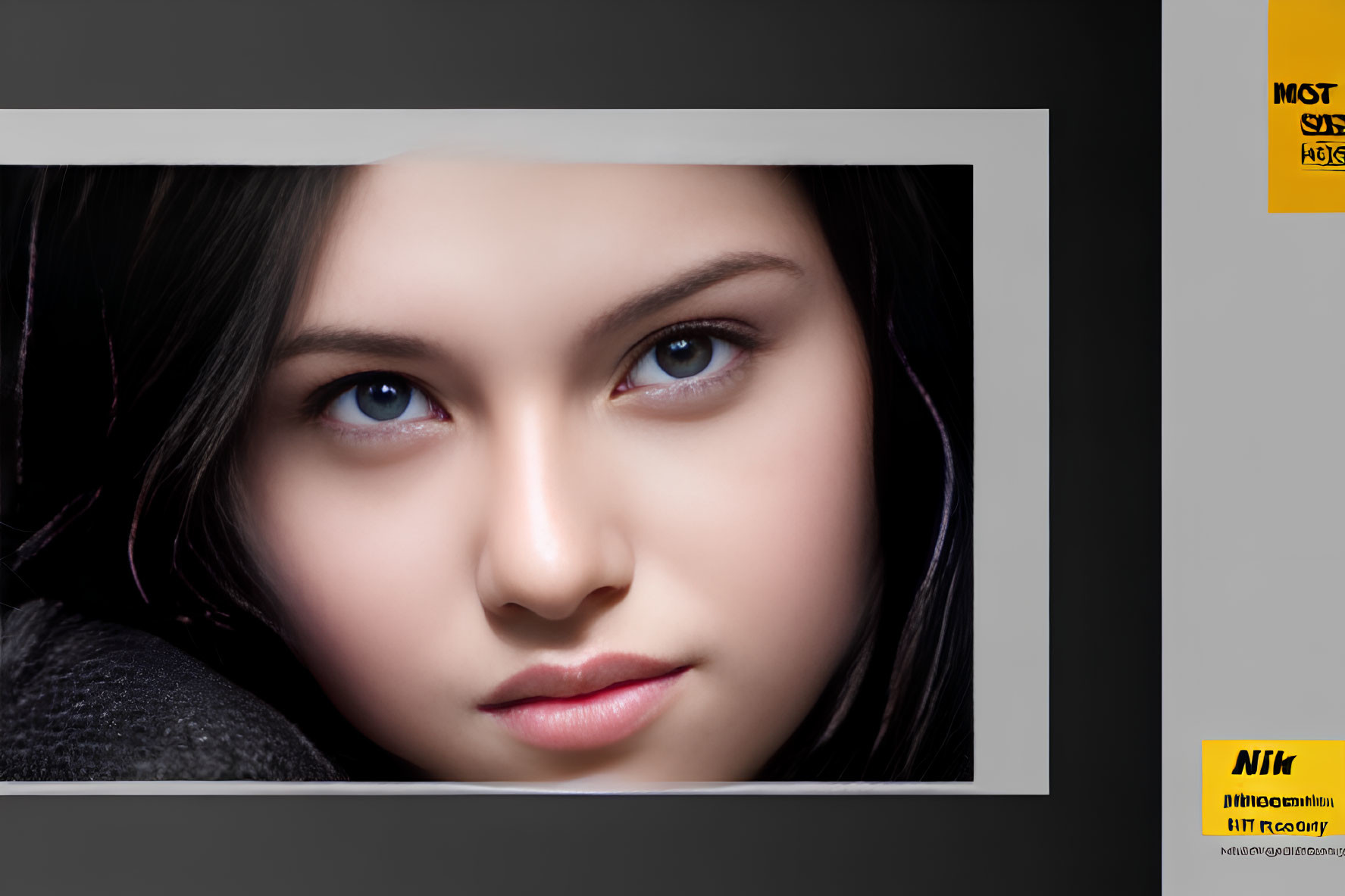 Portrait of young woman with dark hair and striking eyes in torn paper frame