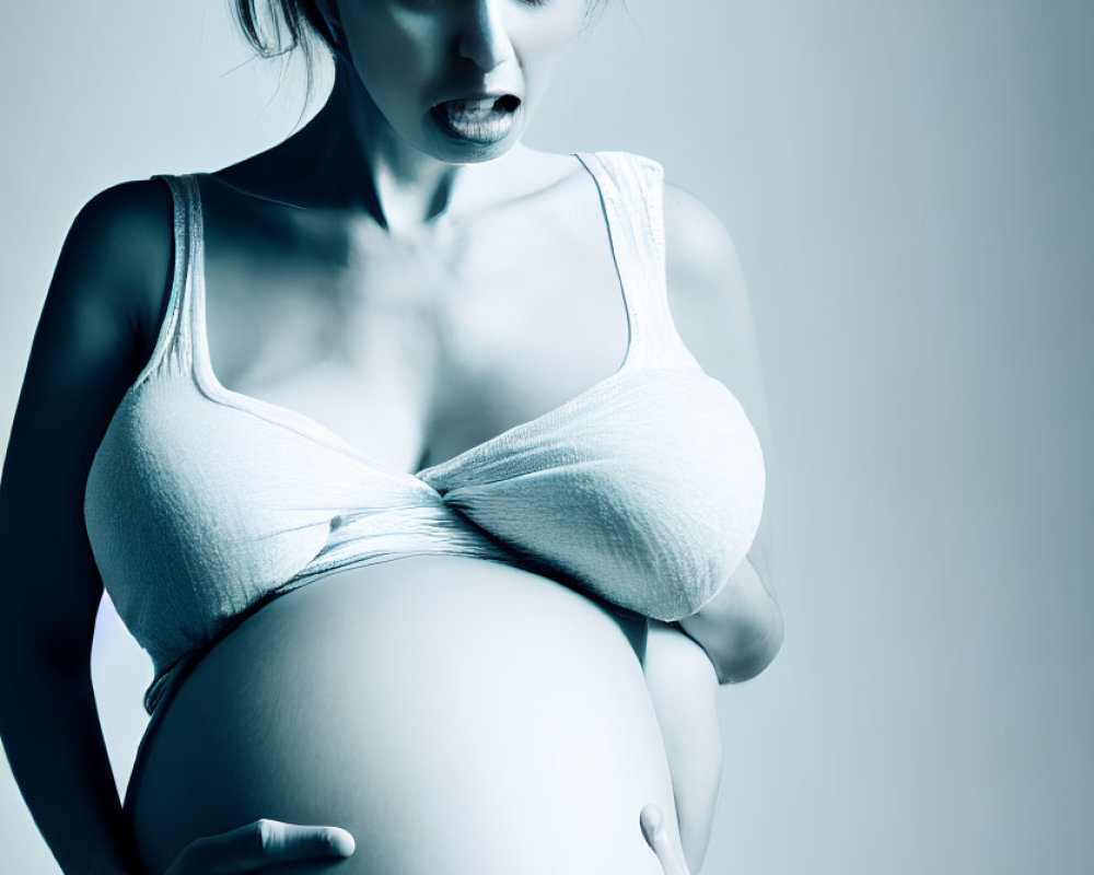 Pregnant Woman Holding Belly with Pained Expression in Cool Blue Tone