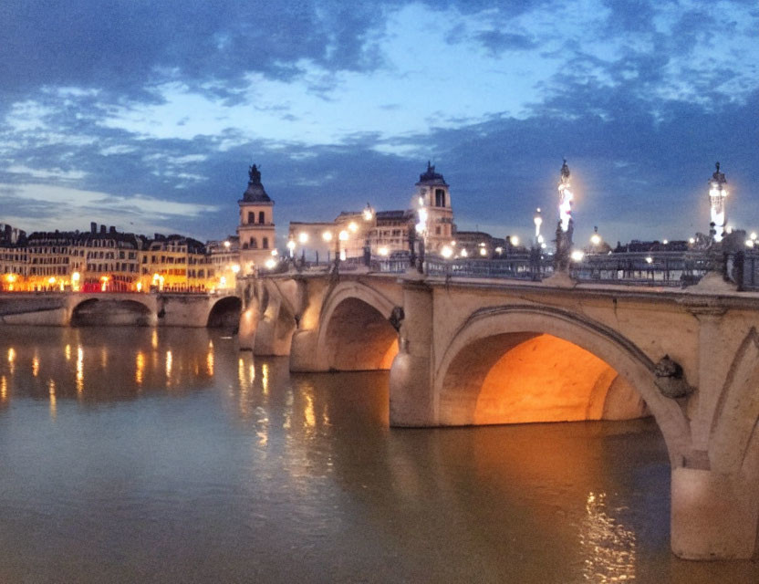 Twilight scene: illuminated bridge, historical buildings, river reflections