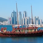 Red cargo ship with colorful containers in busy port with cranes