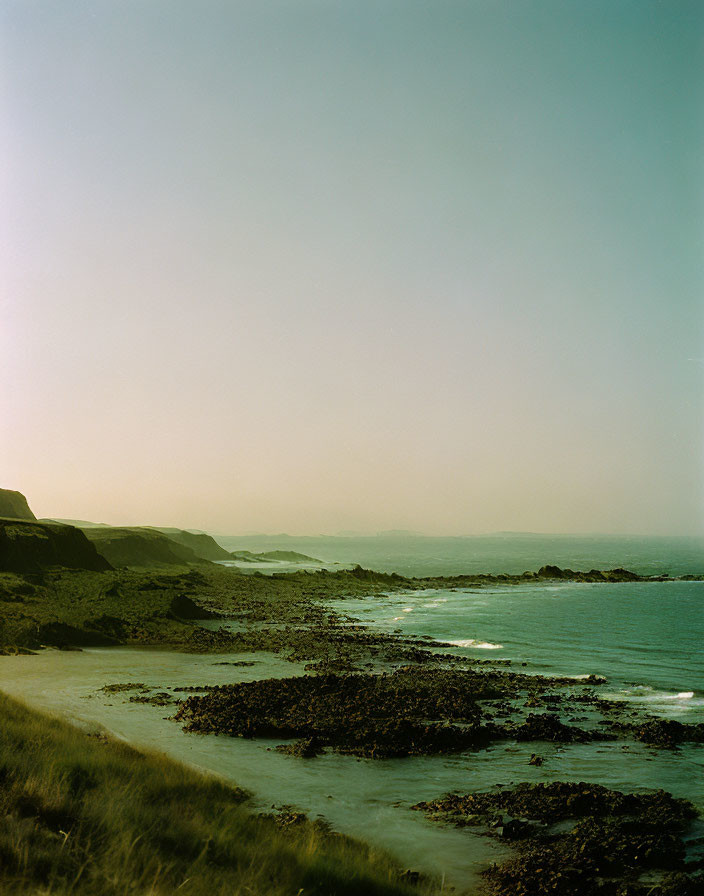 Tranquil Coastal Landscape with Rocky Shoreline & Gradient Sky