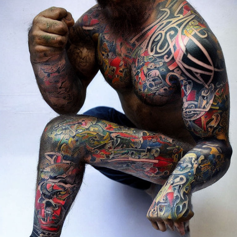 Colorful and intricate upper body and arm tattoos displayed.