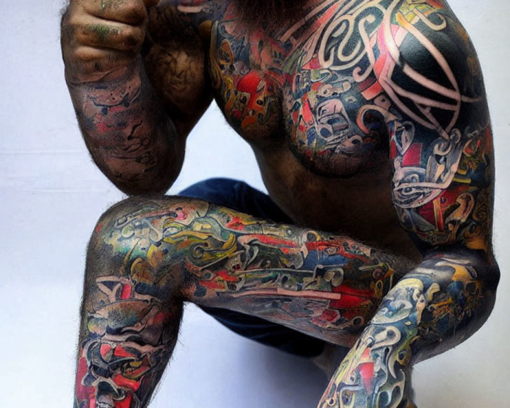 Colorful and intricate upper body and arm tattoos displayed.