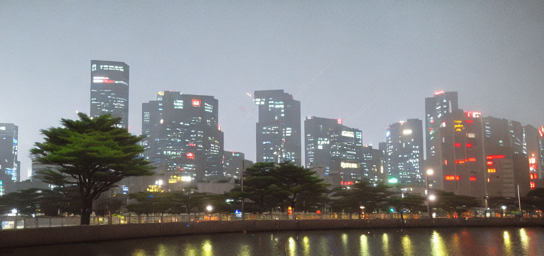 Night cityscape with glowing skyscrapers and fog, reflected in water, tree silhouette.