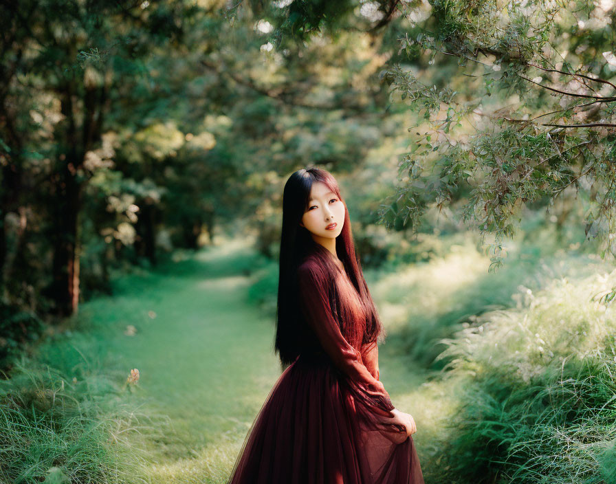 Woman in Burgundy Dress Surrounded by Greenery