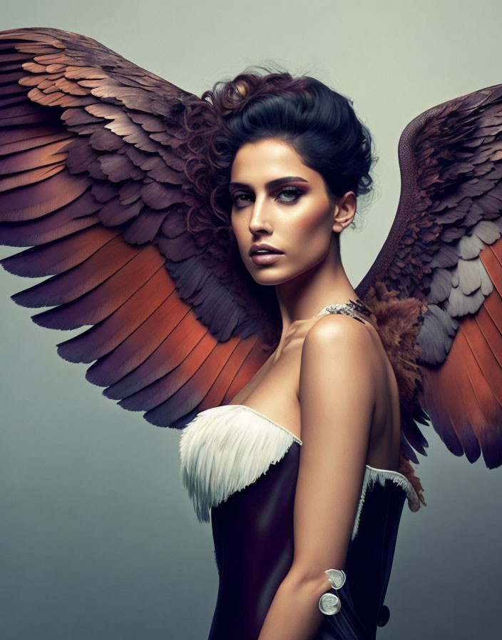 Dark-haired woman with dramatic makeup and angel wings in strapless attire