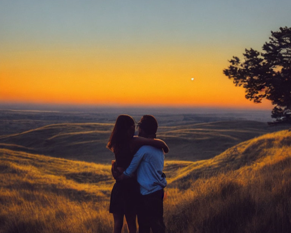 Embracing couple with sunset over hilly landscape