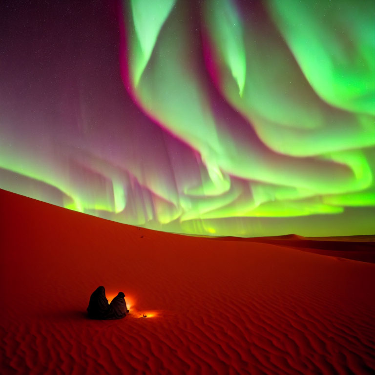 Couple reclining on sand dune under vivid aurora borealis