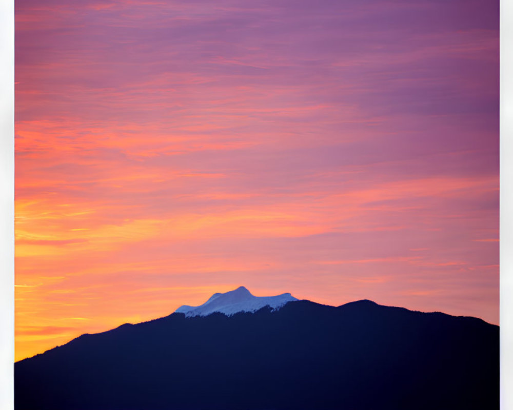 Colorful sunset over purple and orange mountains reflected in calm water