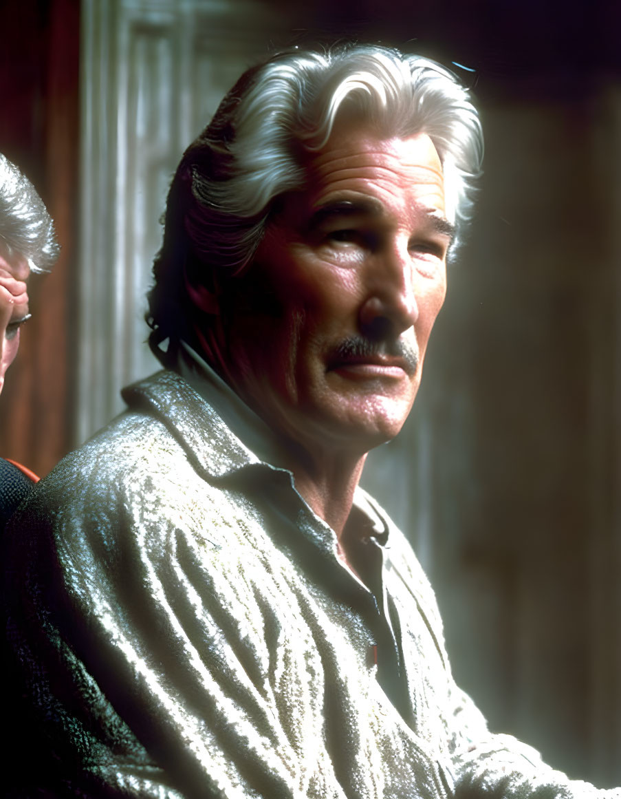 Elderly man with white mustache and styled hair in warm lighting