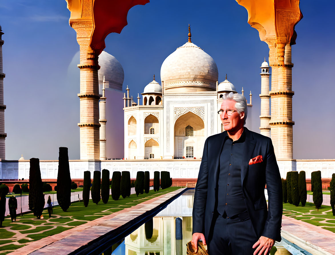 Man in suit with red pocket square smiling at Taj Mahal under vibrant arches