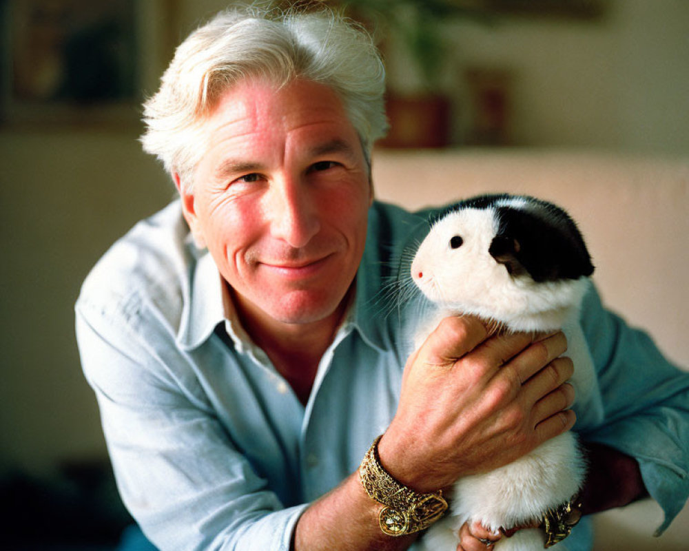 Silver-Haired Man Smiling with Guinea Pig and Blue Shirt